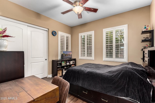 bedroom with baseboards, ceiling fan, a closet, and wood finished floors