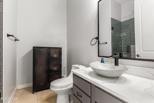 bathroom featuring vanity, toilet, baseboards, tile patterned floors, and a tile shower