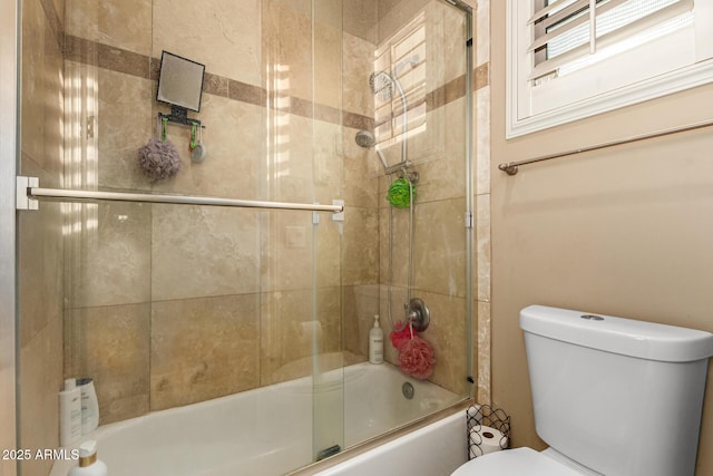 bathroom featuring toilet and combined bath / shower with glass door