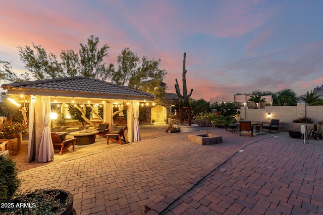 view of patio / terrace featuring a gazebo, fence, and an outdoor living space with a fire pit