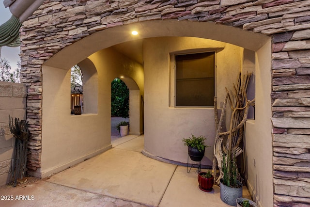 view of exterior entry featuring a patio and stone siding