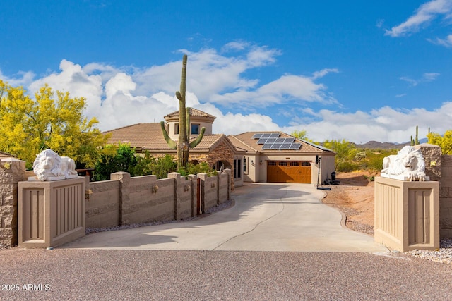 view of front of property with an attached garage, solar panels, a fenced front yard, and a gate