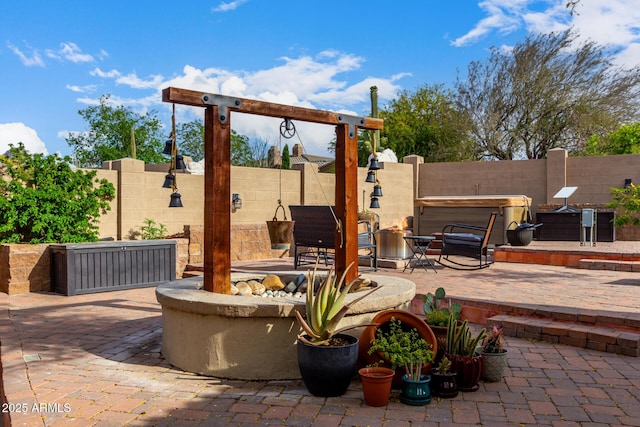 view of patio / terrace featuring a fenced backyard, a hot tub, and an outdoor fire pit