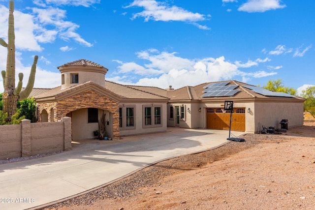 back of house with fence, stucco siding, solar panels, a tiled roof, and driveway