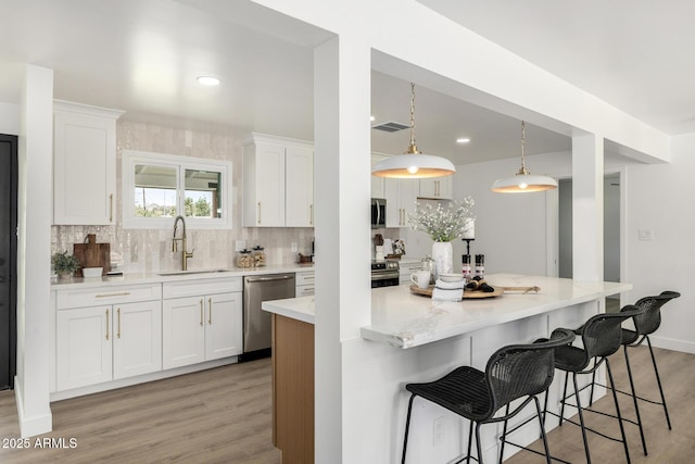 215 W Ruth Ave, Phoenix, AZ 85021 - kitchen featuring appliances with stainless steel finishes, light wood-style flooring, decorative backsplash, white cabinetry, and recessed lighting