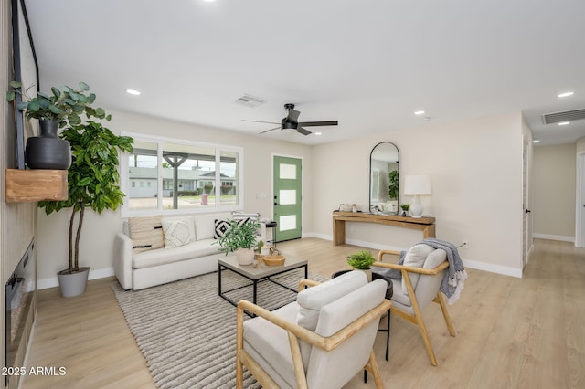 living room featuring light wood-type flooring, a ceiling fan, and visible vents