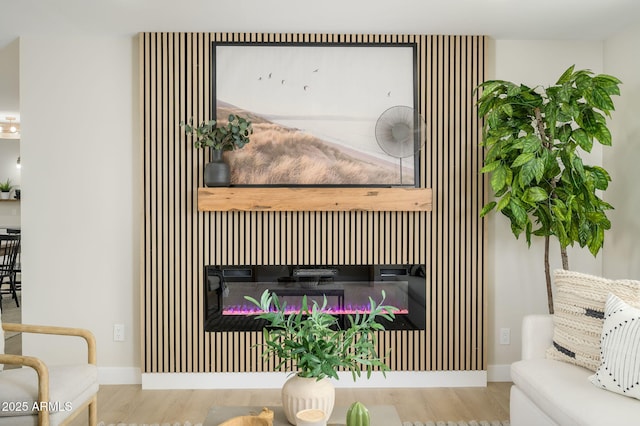 details with baseboards, wood finished floors, and a glass covered fireplace