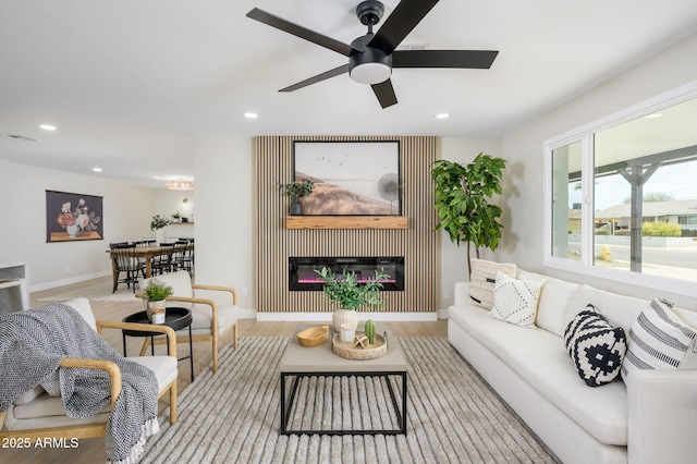 living area featuring recessed lighting, baseboards, visible vents, a glass covered fireplace, and ceiling fan