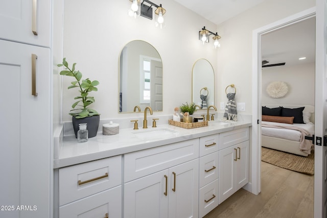 bathroom featuring ensuite bathroom, double vanity, a sink, and wood finished floors