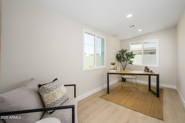 home office with visible vents, wood finished floors, vaulted ceiling, and plenty of natural light