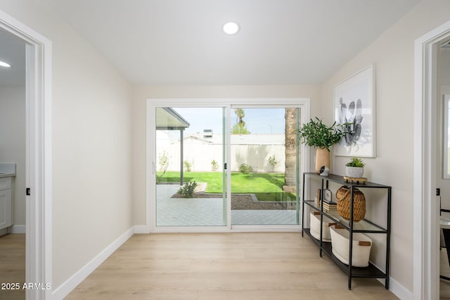 doorway to outside featuring light wood finished floors, baseboards, and recessed lighting