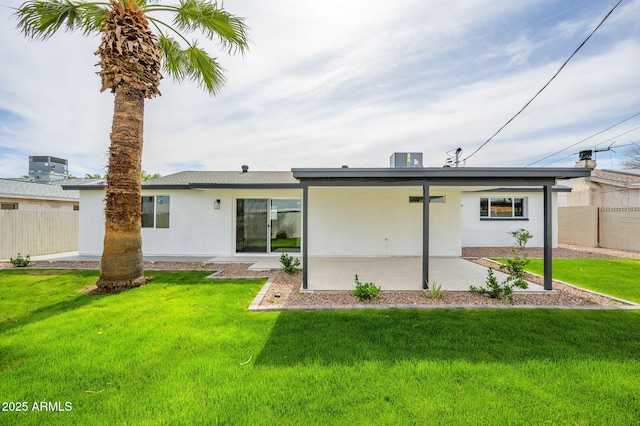 rear view of property featuring stucco siding, fence, a yard, and a patio area