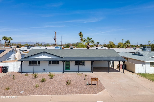 single story home featuring concrete driveway, central air condition unit, fence, a residential view, and a carport