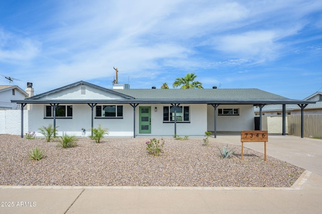 ranch-style house with driveway, a carport, fence, and stucco siding
