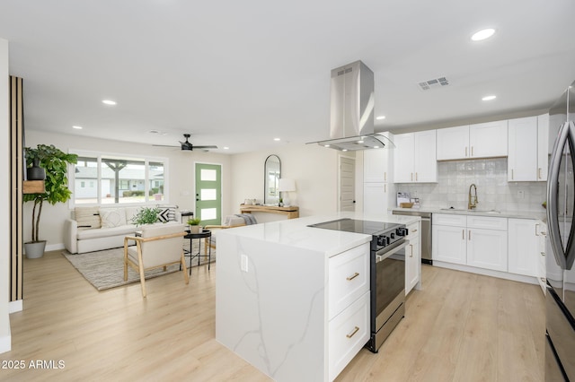 kitchen featuring visible vents, ceiling fan, stainless steel appliances, a sink, and island range hood