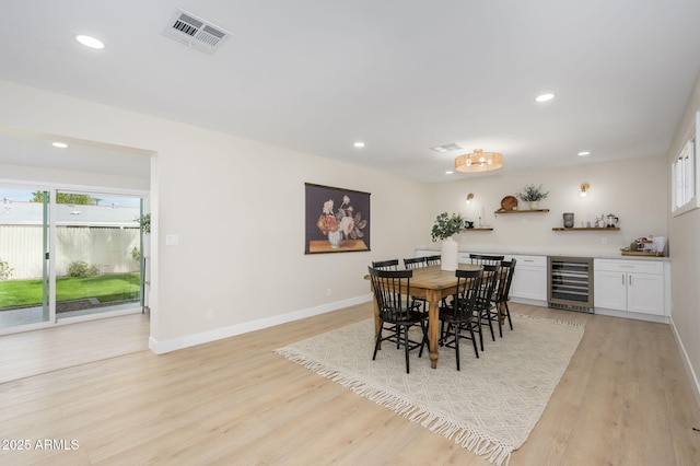 dining space featuring recessed lighting, wine cooler, light wood finished floors, visible vents, and a bar