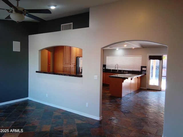 kitchen featuring stainless steel fridge, baseboards, visible vents, dark countertops, and stone tile flooring