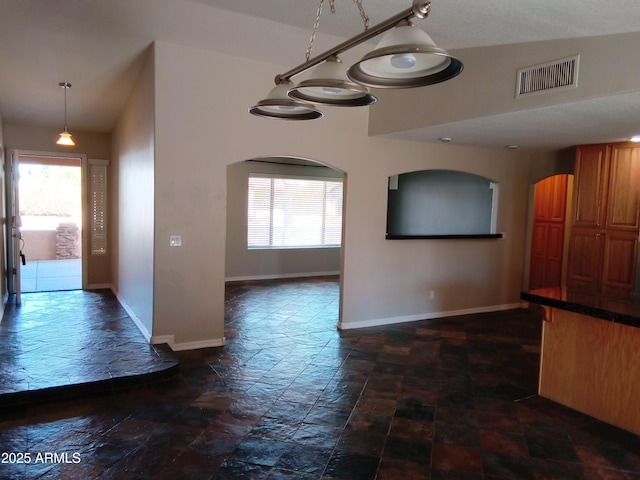 interior space featuring stone finish floor, baseboards, visible vents, and a wealth of natural light