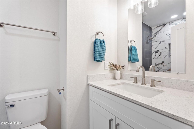 bathroom with vanity, toilet, and a tile shower