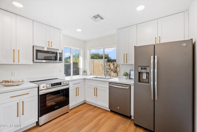 kitchen featuring white cabinetry, appliances with stainless steel finishes, light hardwood / wood-style floors, and sink