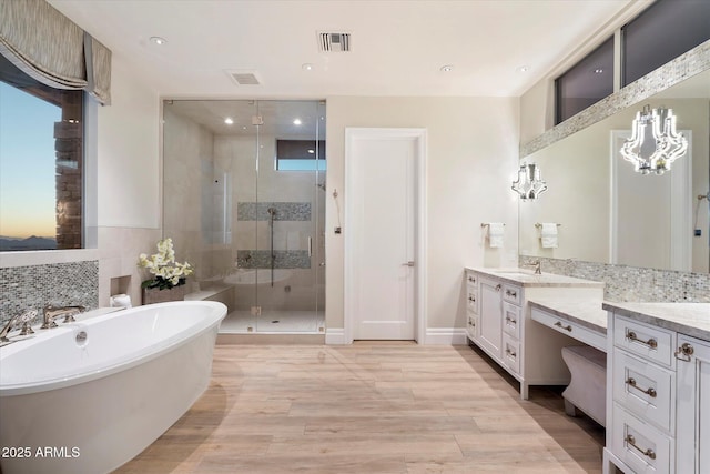 bathroom with visible vents, wood finished floors, a freestanding bath, vanity, and a shower stall