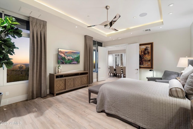 bedroom featuring baseboards, visible vents, a tray ceiling, light wood-type flooring, and recessed lighting