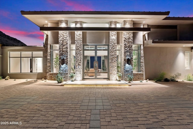 entrance to property featuring stone siding and stucco siding