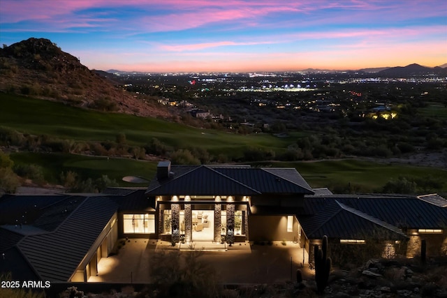 back of property at dusk featuring metal roof, a patio area, and a mountain view