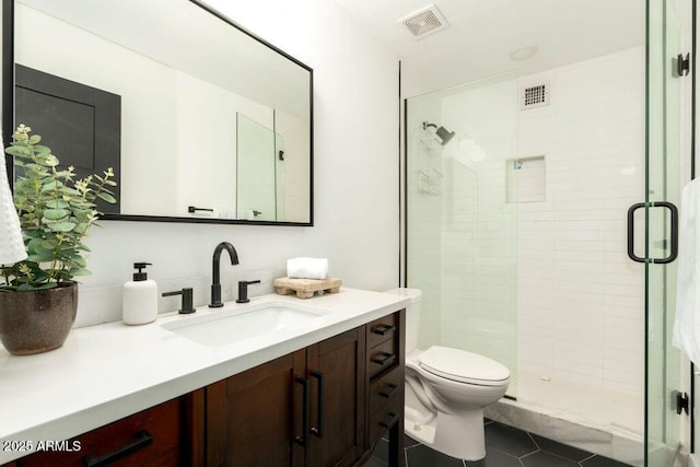 bathroom with tile patterned floors, vanity, an enclosed shower, and toilet