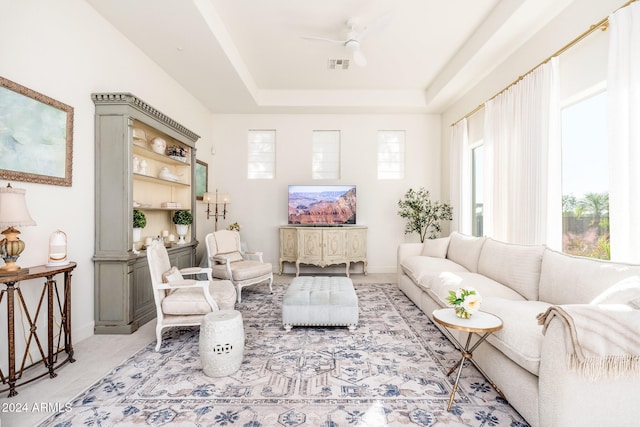 living room featuring ceiling fan and a tray ceiling