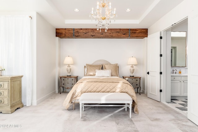 bedroom featuring a raised ceiling, ensuite bath, sink, and an inviting chandelier