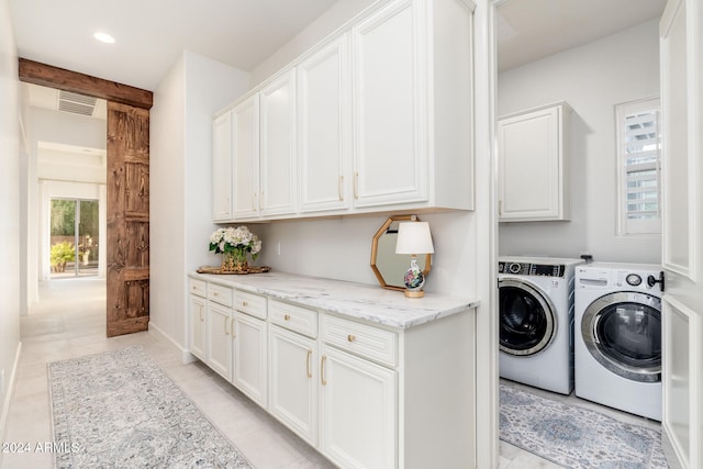 clothes washing area featuring washer and dryer, light tile patterned flooring, and cabinets