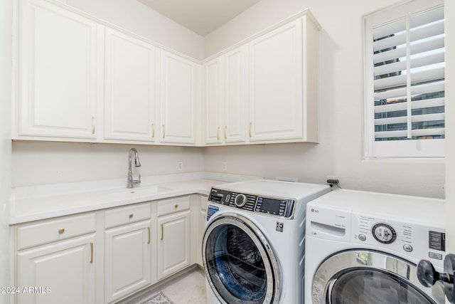 clothes washing area with cabinets, washing machine and dryer, and sink