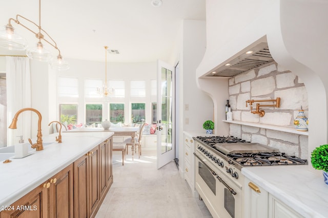 kitchen with pendant lighting, high end range, backsplash, a notable chandelier, and light stone counters