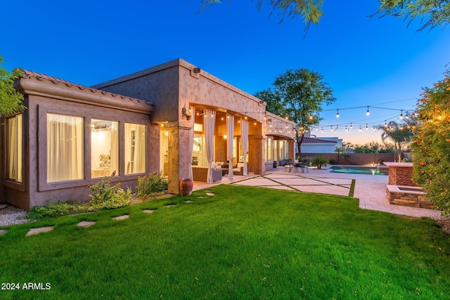 back house at dusk with a lawn, a fenced in pool, and a patio