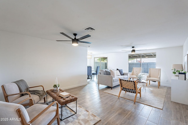 living room with a ceiling fan, baseboards, visible vents, and light wood finished floors