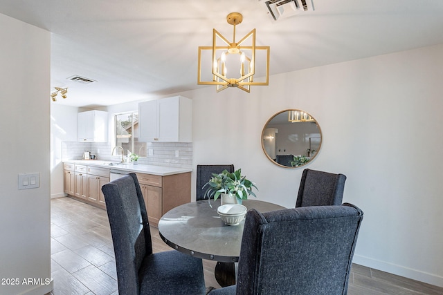 dining space with visible vents, a notable chandelier, light wood finished floors, and baseboards