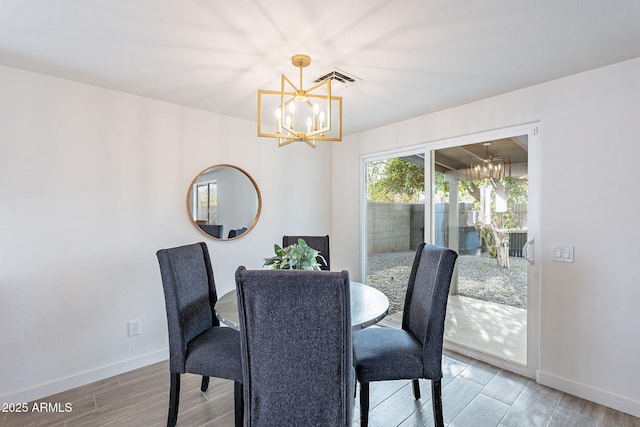 dining area featuring baseboards, wood finished floors, and an inviting chandelier