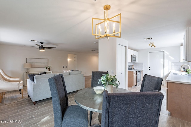 dining area with ceiling fan with notable chandelier, visible vents, and wood tiled floor