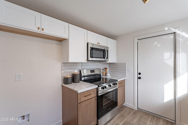 kitchen with stainless steel appliances, white cabinetry, baseboards, light wood-type flooring, and tasteful backsplash