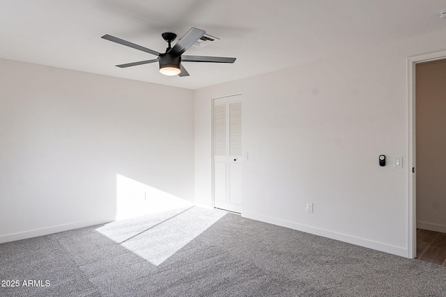 carpeted spare room featuring a ceiling fan and baseboards