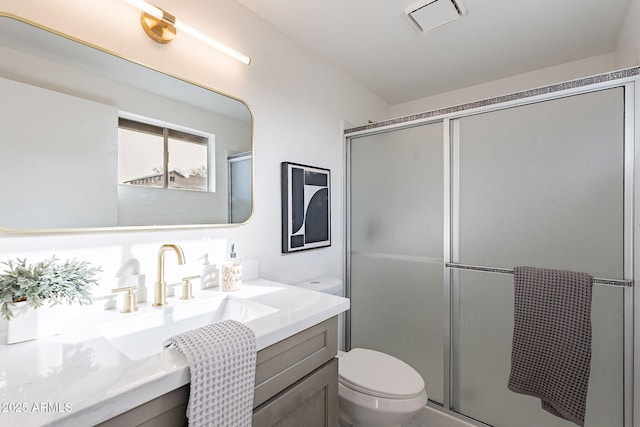 bathroom featuring visible vents, vanity, a shower stall, and toilet