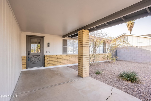 doorway to property featuring a patio area, fence, and brick siding