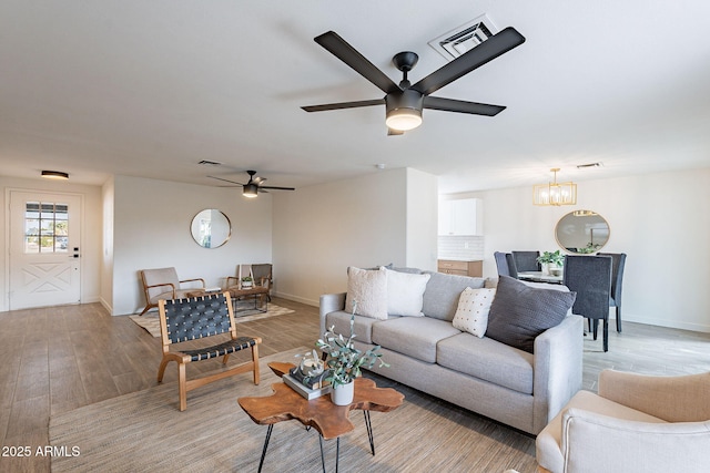 living area featuring light wood-style flooring, visible vents, and baseboards