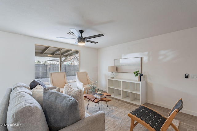 living room with a ceiling fan, baseboards, and wood finished floors