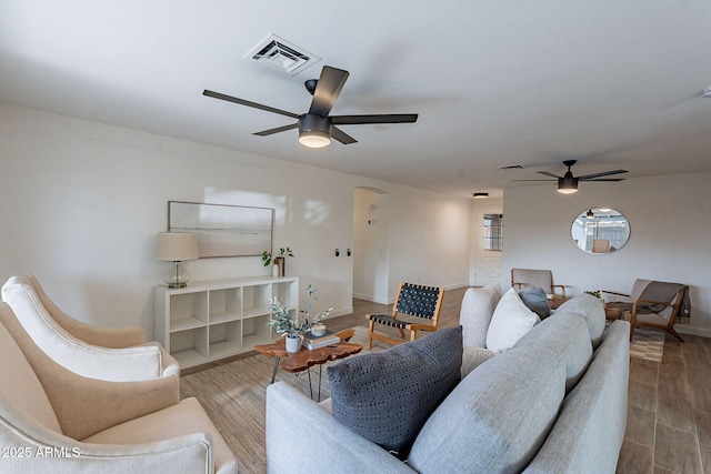 living area featuring a ceiling fan, wood finished floors, visible vents, and baseboards