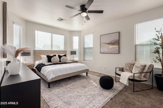 carpeted bedroom with a ceiling fan, visible vents, baseboards, and multiple windows