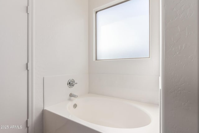 bathroom with a textured wall and a bath