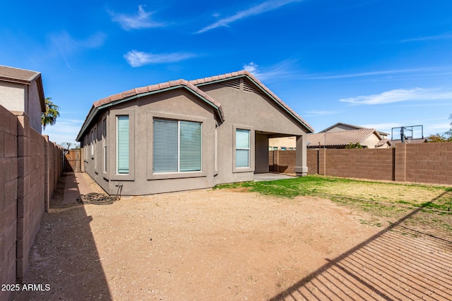 rear view of property featuring a patio, a tile roof, a fenced backyard, and stucco siding