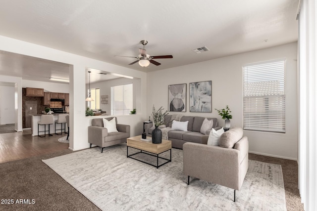 living room with carpet, visible vents, and a ceiling fan